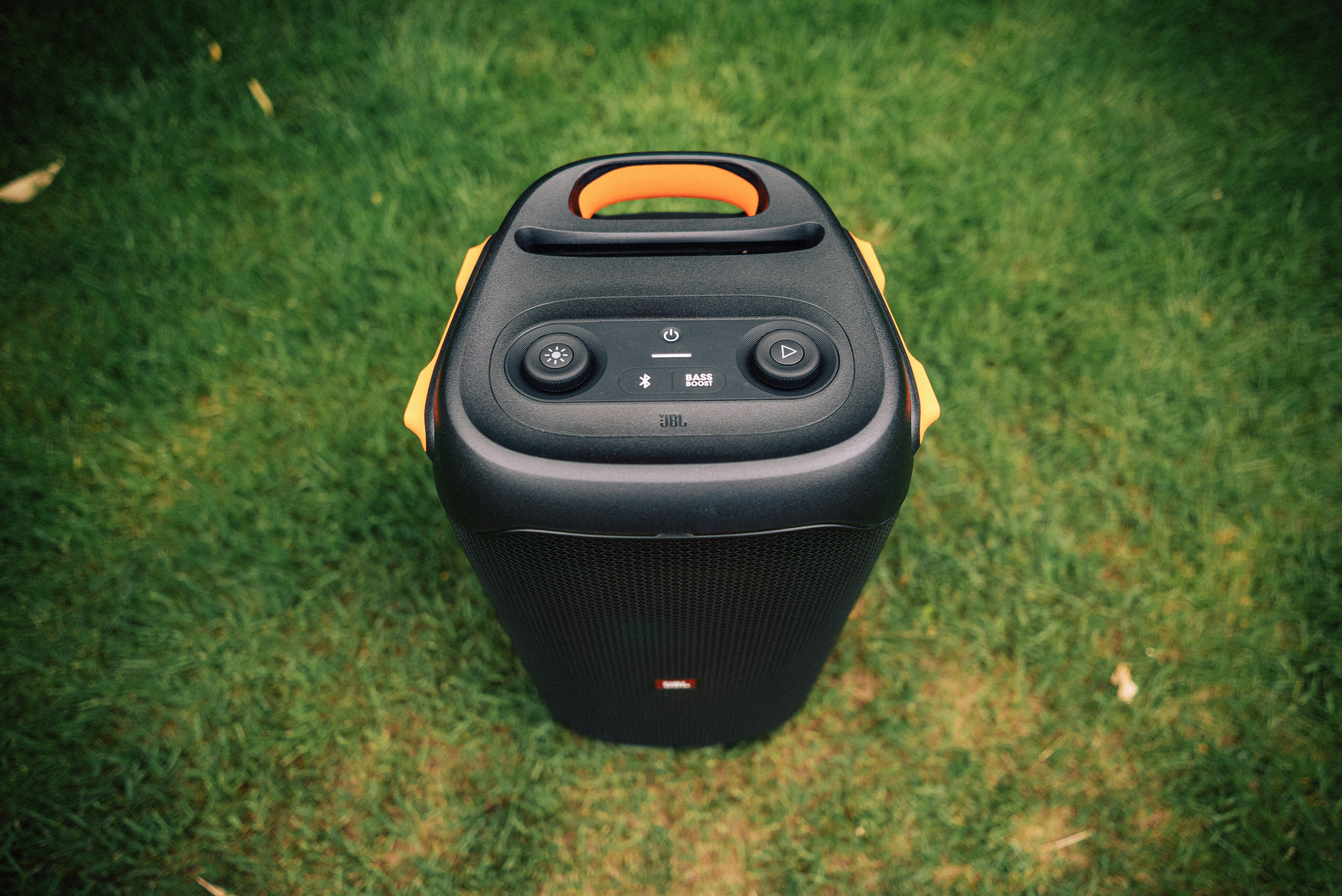 a black and yellow speaker sitting on top of a lush green field