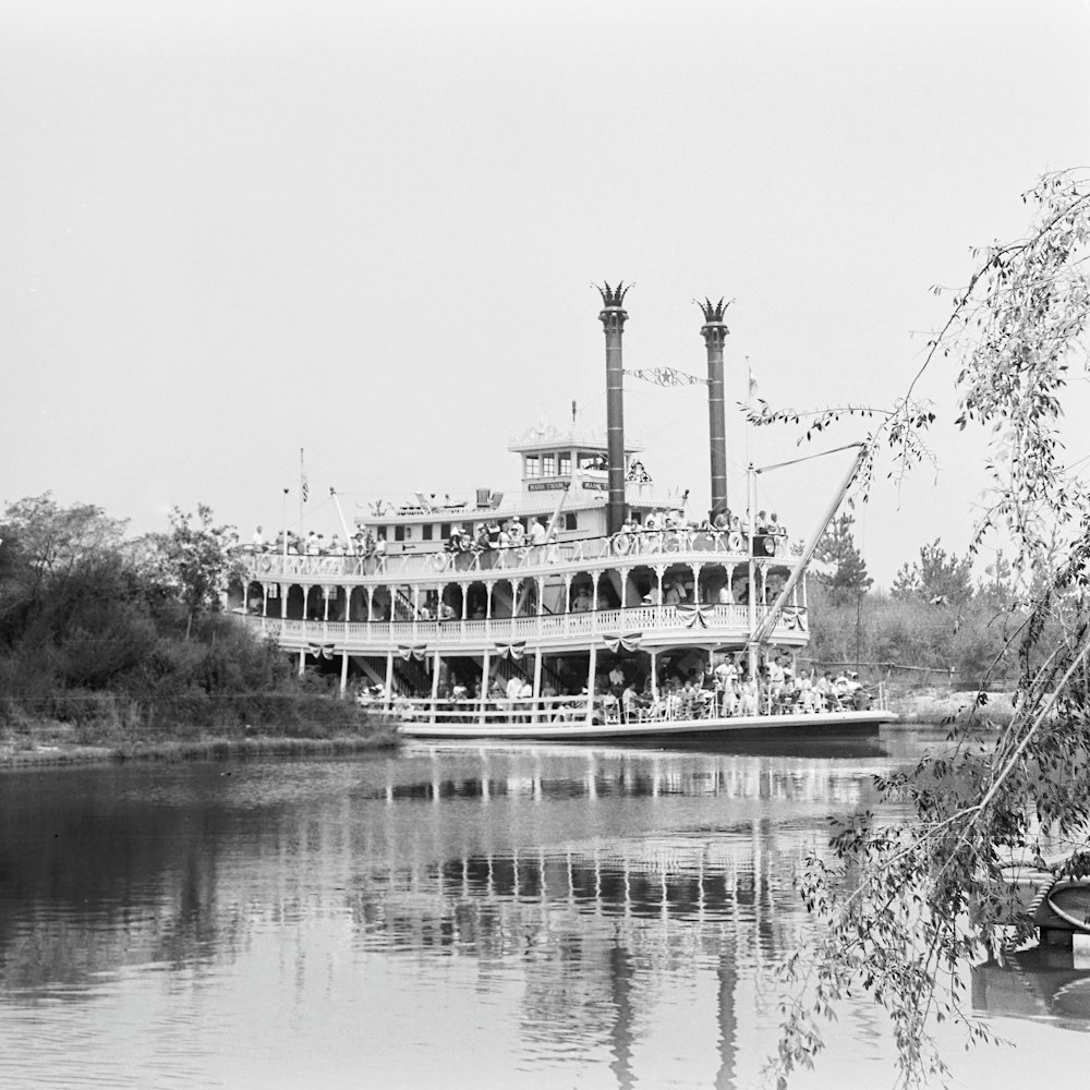 a large boat floating on top of a river next to a forest