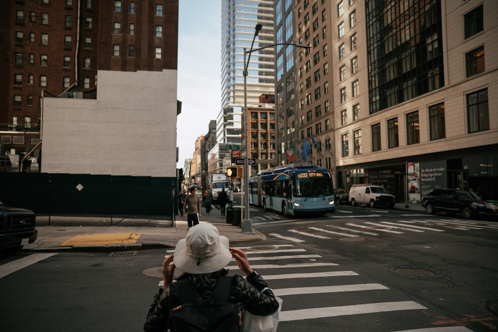 a woman walking across a street next to tall buildings