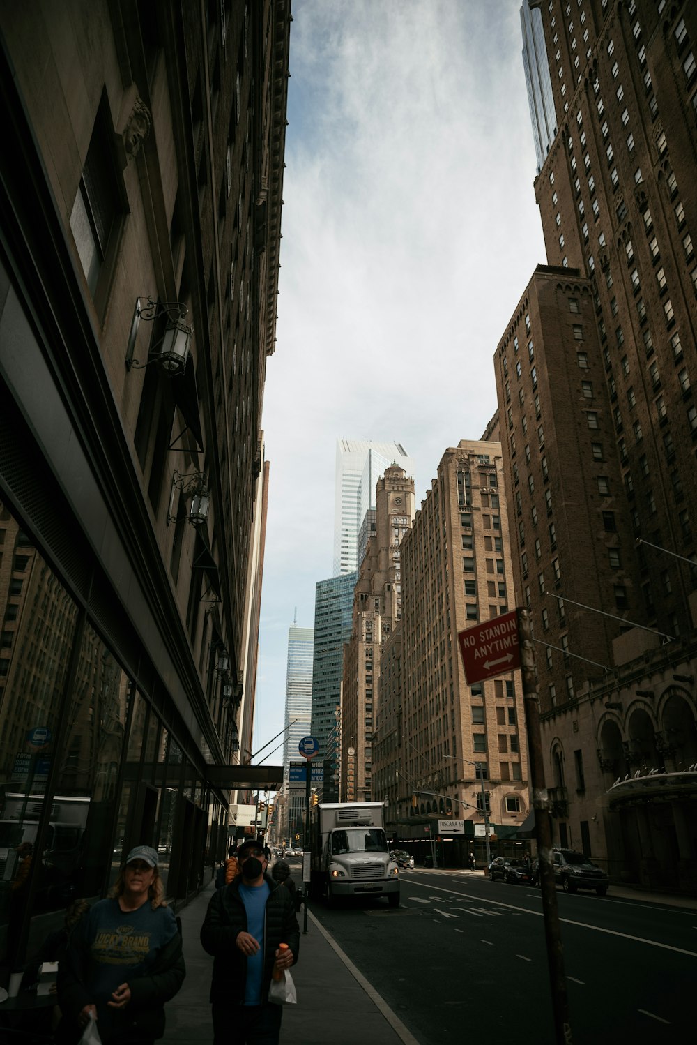 a couple of people walking down a street next to tall buildings