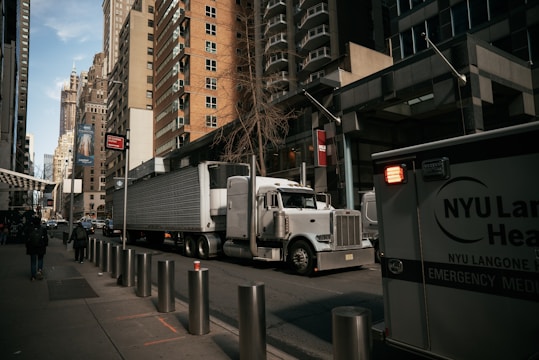A cargo truck navigating through urban streets with buildings and traffic around.