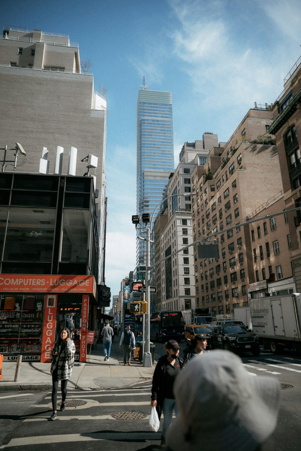 a group of people walking across a street next to tall buildings