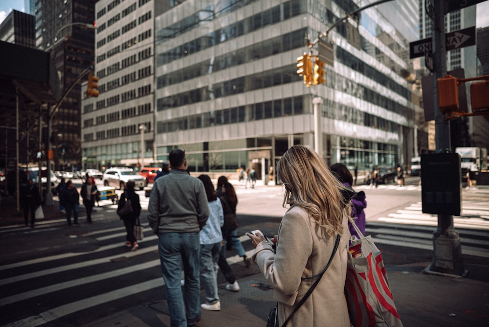 a group of people walking across a street next to tall buildings