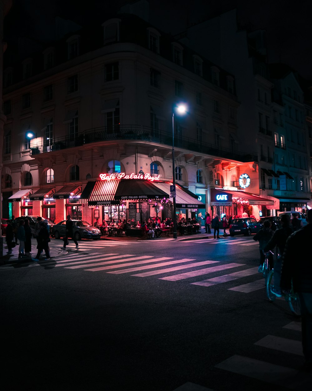 a group of people walking across a street at night