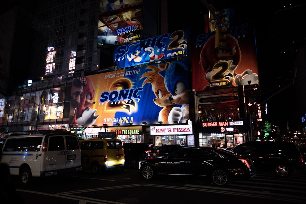 Una strada cittadina di notte con auto e cartelloni pubblicitari