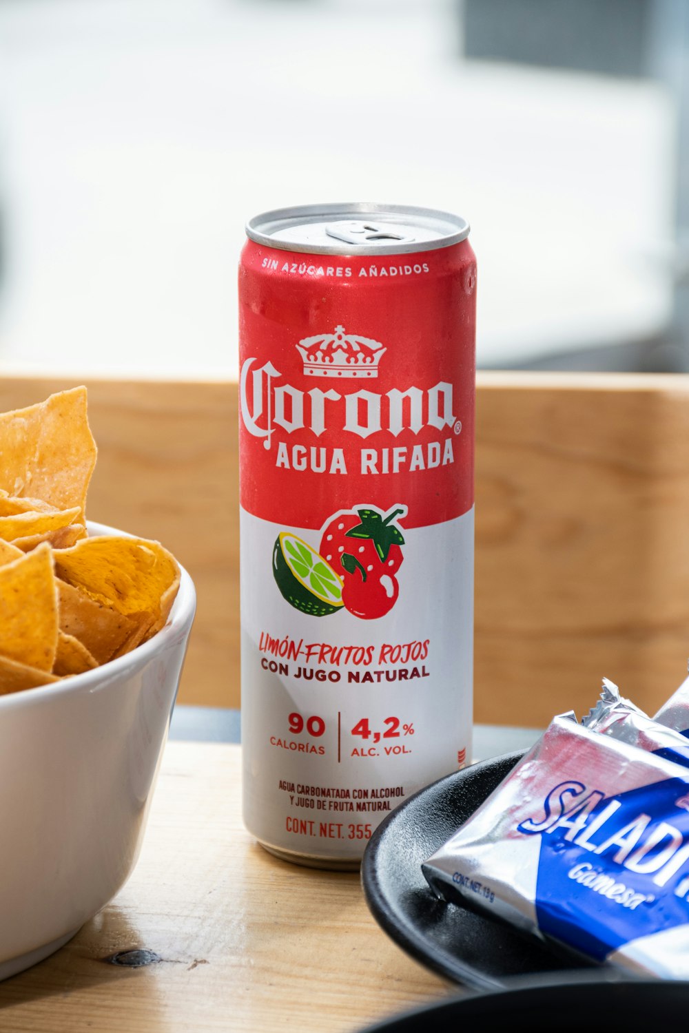a bowl of tortilla chips next to a can of corona