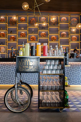 A sleek, modern mobile beverage bar styled with navy, red, and teal accents, set against a backdrop featuring subtle topographic line patterns.
