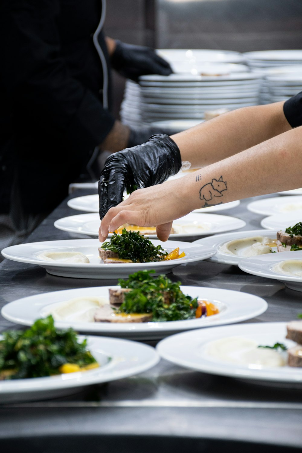 a person in black gloves putting food on a plate
