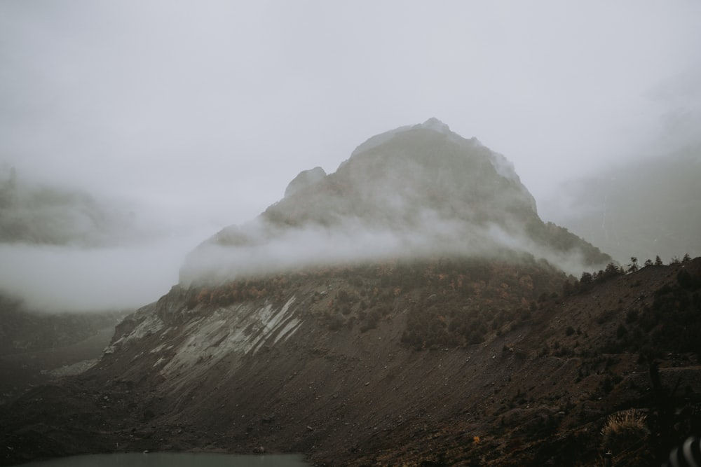 a foggy mountain with a lake in the foreground