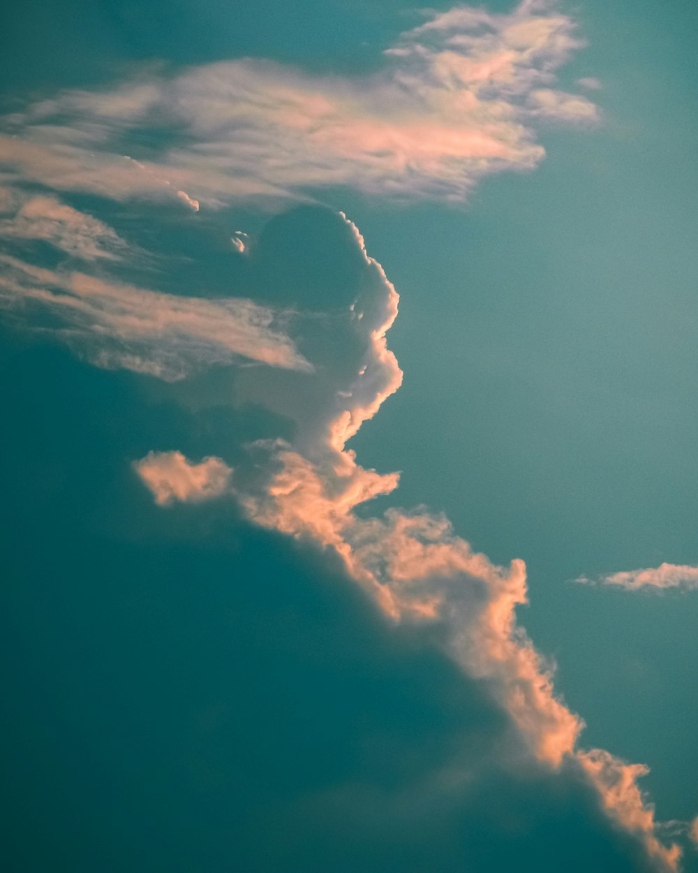 a plane flying through a cloudy blue sky