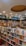 A well-organized bookstore interior with shelves full of diverse books. The sections include categories like Business & Management, Self Help, Indian Fiction, Crime & Mystery, and Bestsellers. The ceiling features recessed lighting and a circular design element.
