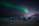 A happy couple enjoying a snowy night with the northern lights glowing above in Lapland.