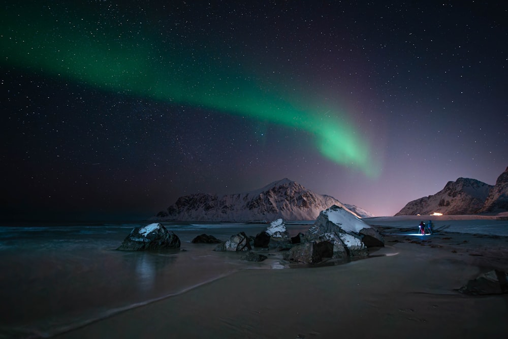 a green and blue aurora above a snowy mountain range