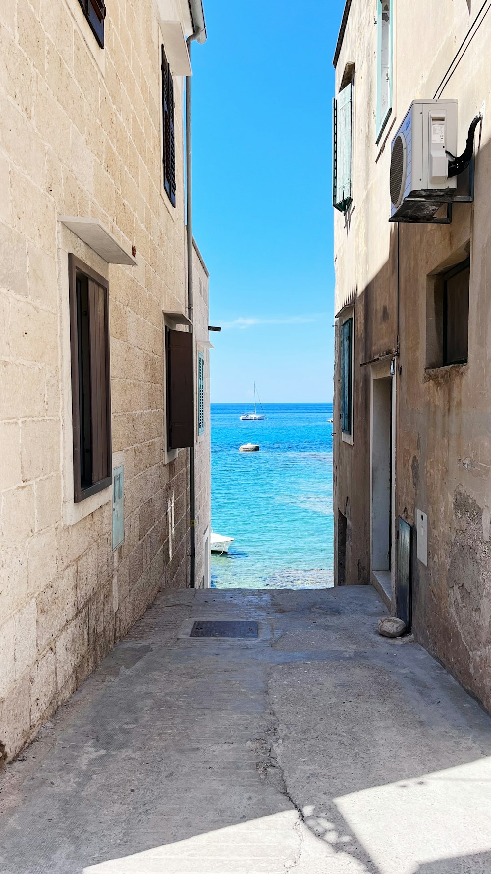 uno stretto vicolo che conduce a una spiaggia con una barca nell'acqua