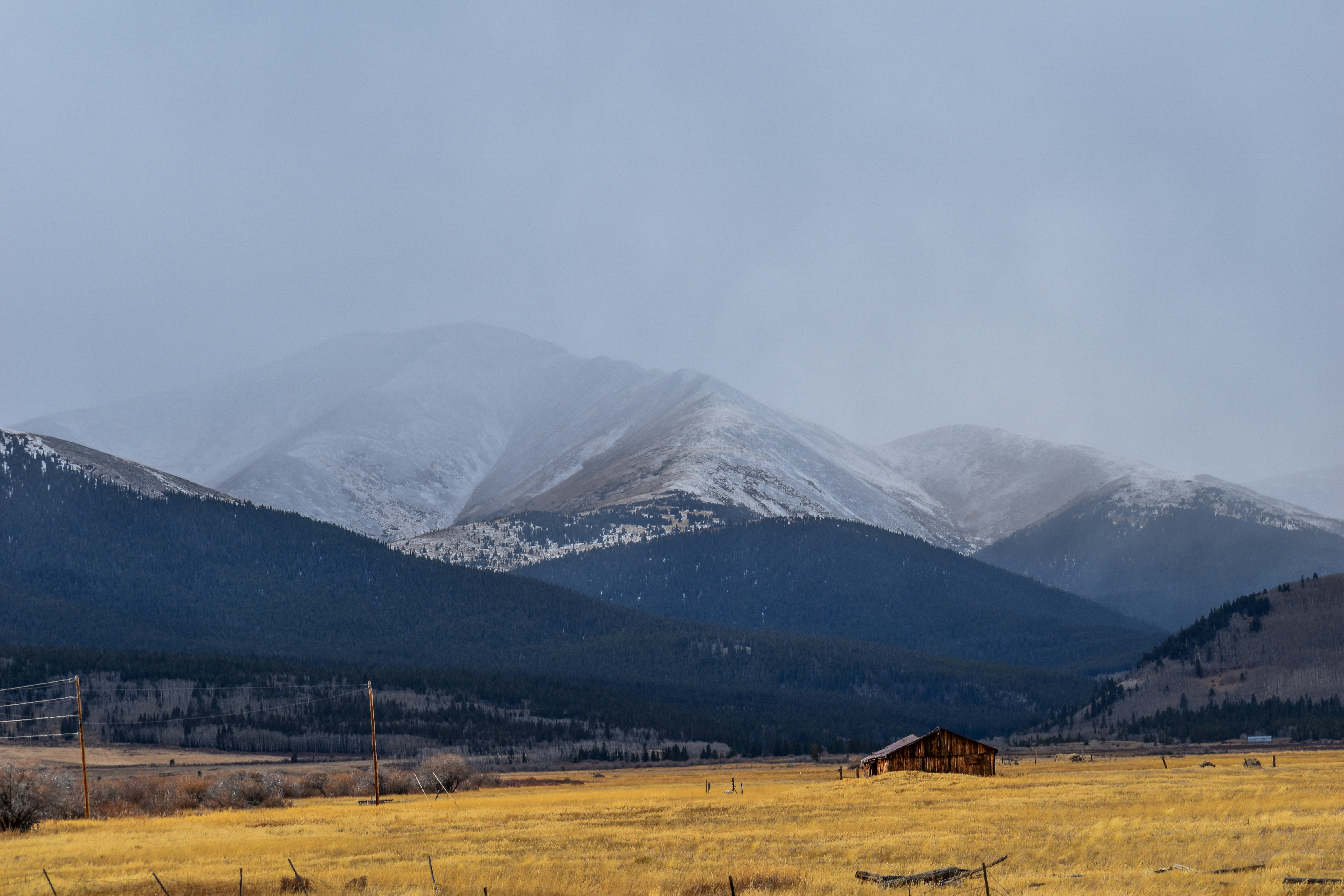 a field with a house and mountains in the background