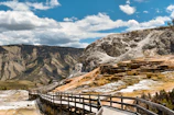 a wooden walkway leading to a mountain with snow on it