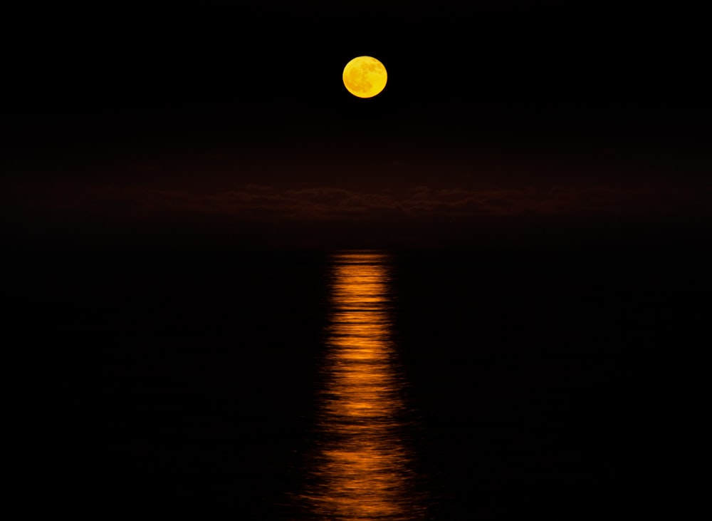 a full moon is reflected in the water
