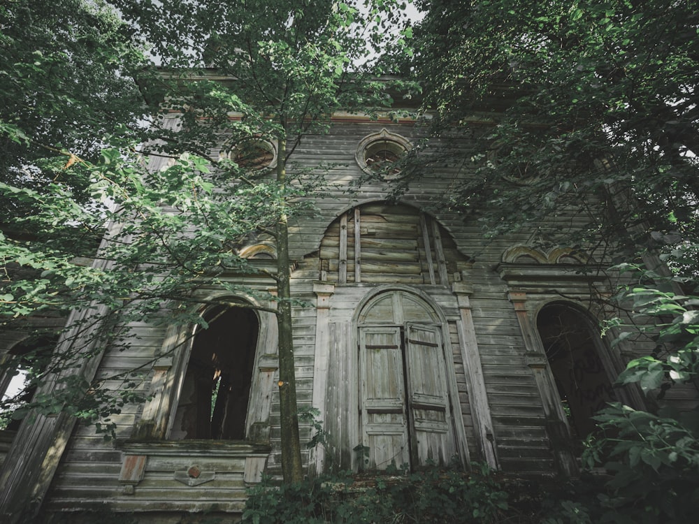 an old building with a wooden door surrounded by trees