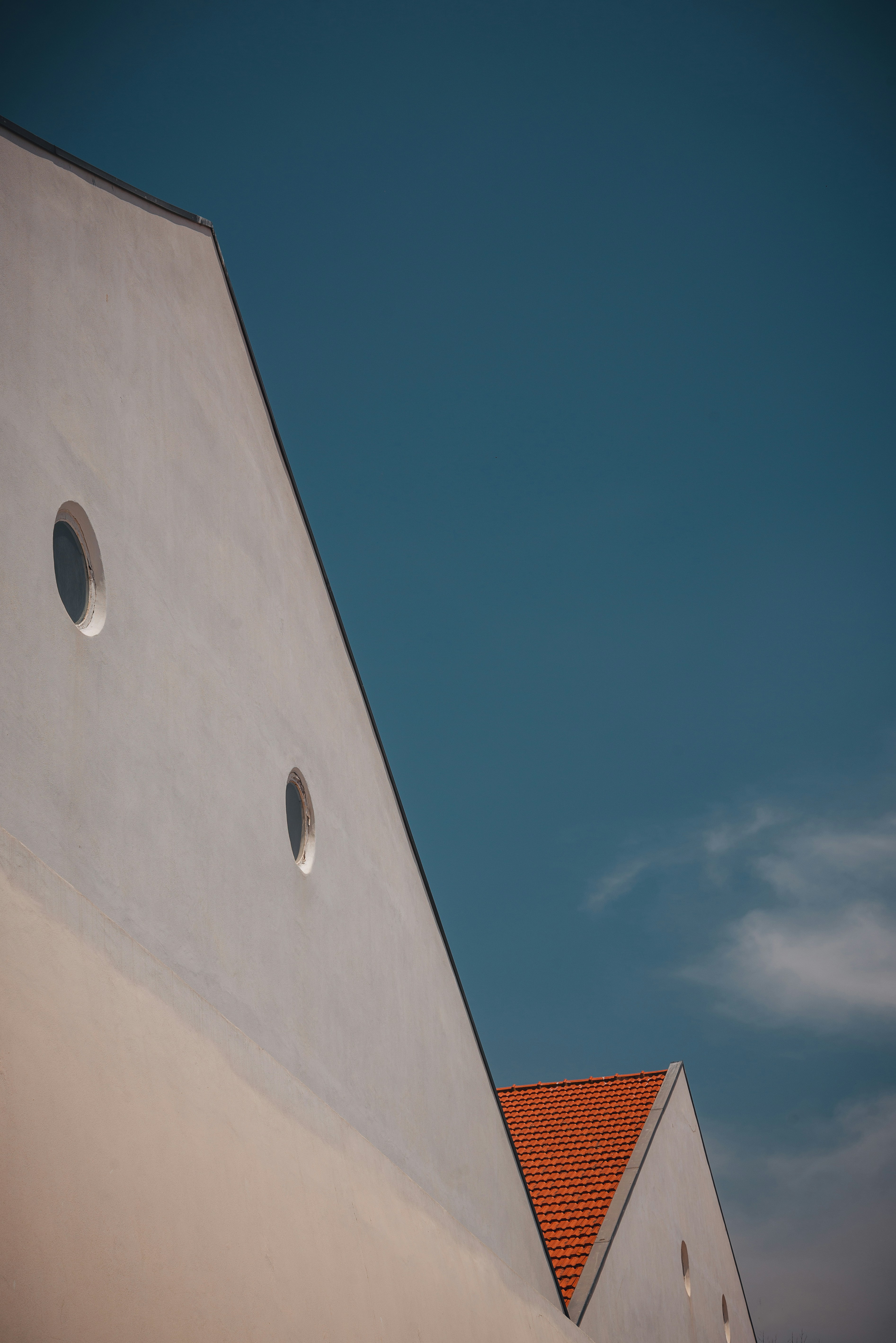 a white building with two round windows and a red roof