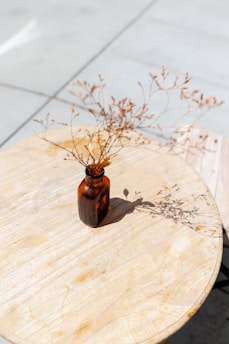 Close-up of a handcrafted herbal tincture bottle beside fresh botanicals and softly glowing candles.