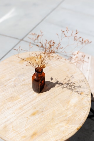 Close-up of a glass bottle of teddyclub ayurvedic bear surrounded by fresh herbs on a wooden surface with soft natural light.