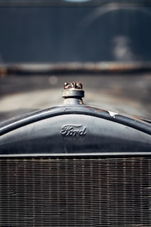 Close-up of the front grille of a vintage Ford automobile, with a clearly visible Ford logo and radiator cap.