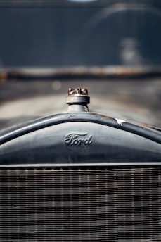 Close-up of the front grille of a vintage Ford automobile, with a clearly visible Ford logo and radiator cap.