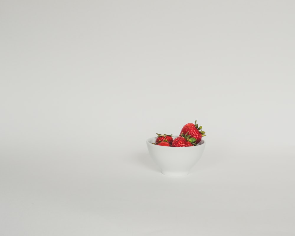 a bowl of strawberries on a white background