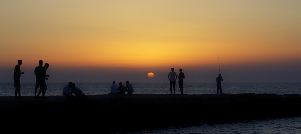 a group of people standing on top of a pier next to the ocean