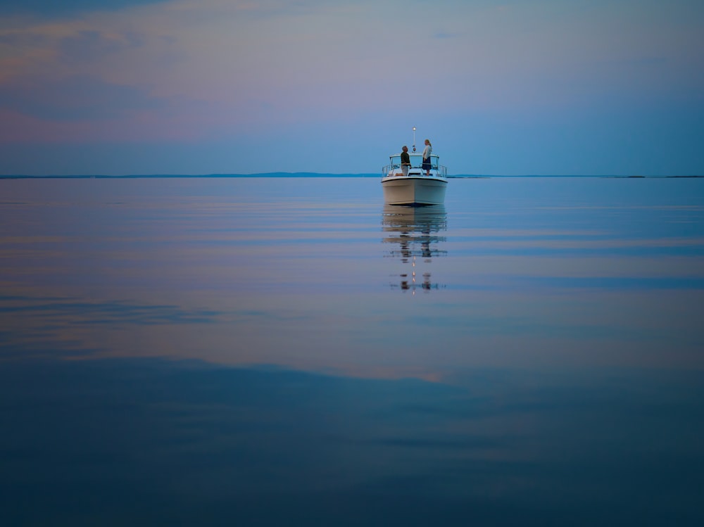 two people standing on a boat in the middle of the ocean