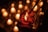 A hand holds a red glass jar containing a lit candle, surrounded by the warm glow of numerous unfocused candles in the background creating a soft, intimate ambiance.