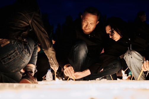 A group of young people lighting neshama lights candles in a quiet remembrance ceremony.