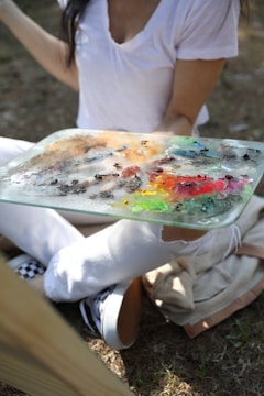 a woman sitting on the ground holding a glass plate