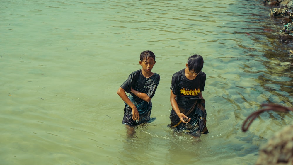 a couple of kids standing in a body of water