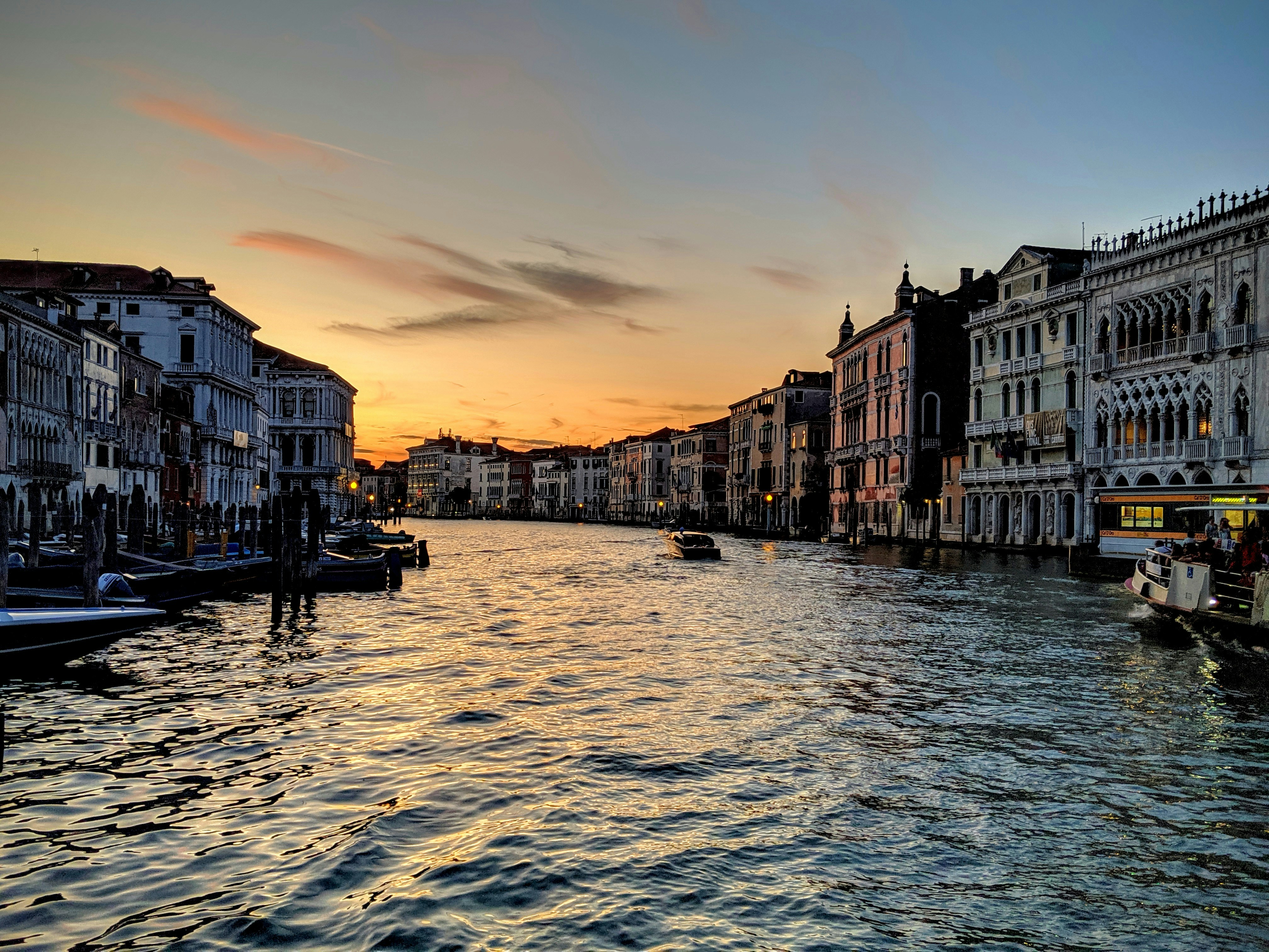 Venice Grand Canal at golden hour with gondolas gliding past ornate Renaissance palaces, reflections shimmering on the water