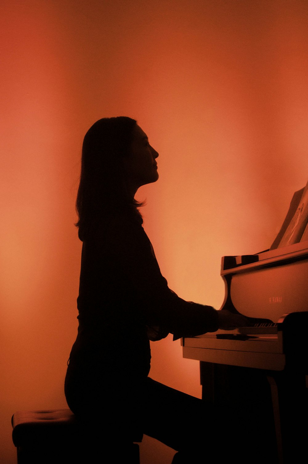 a silhouette of a woman playing a piano