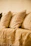 A close-up of soft, colorful throw pillows arranged on a comfy sofa in a sunlit living room.