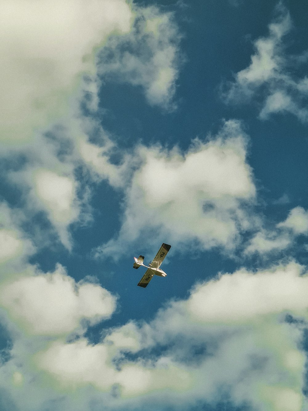 Un pequeño avión volando a través de un cielo azul nublado