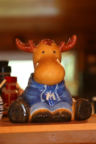 Close-up of hand-painted moose-themed ceramic mugs on a wooden shelf.