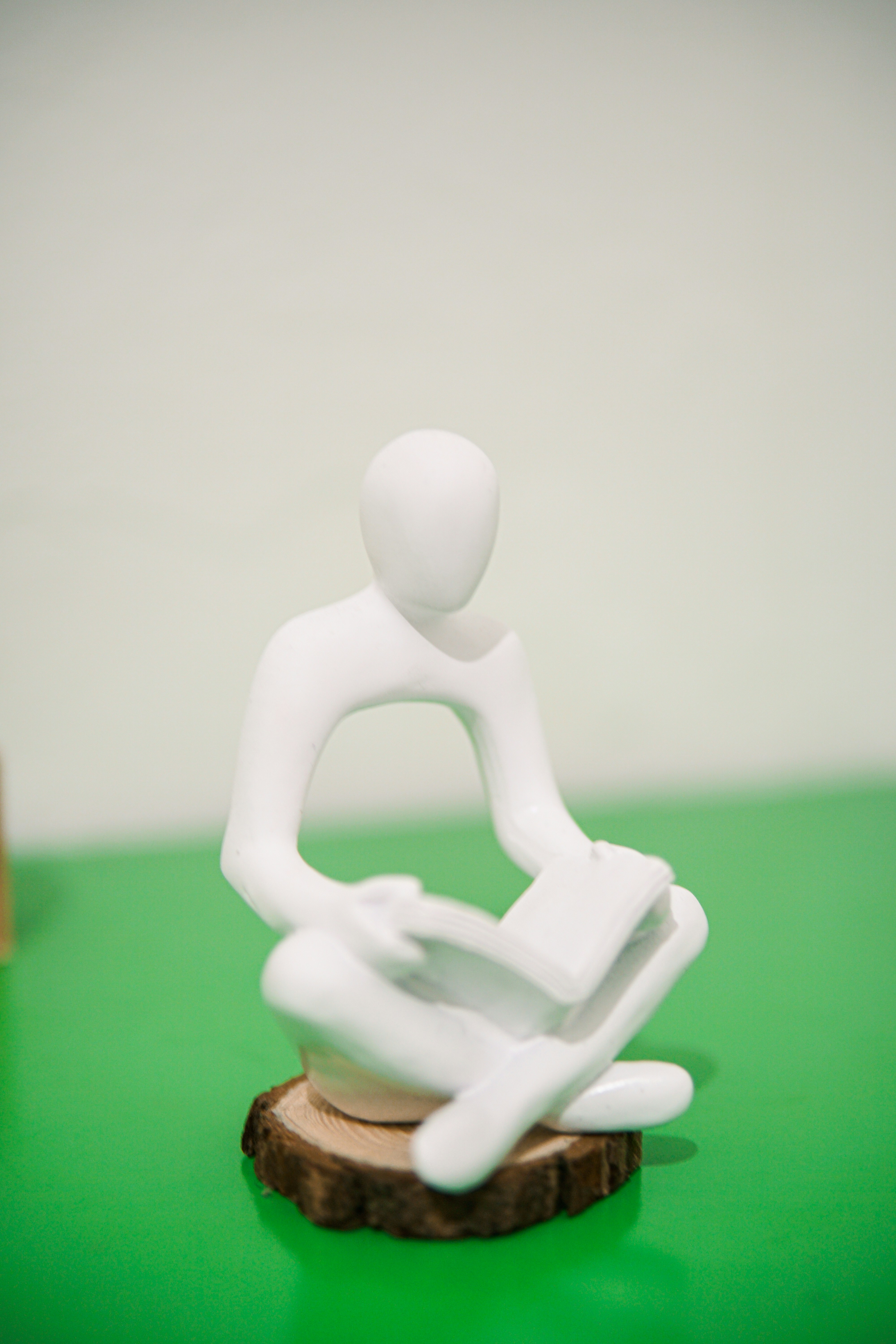 a white plastic figure sitting on a piece of wood
