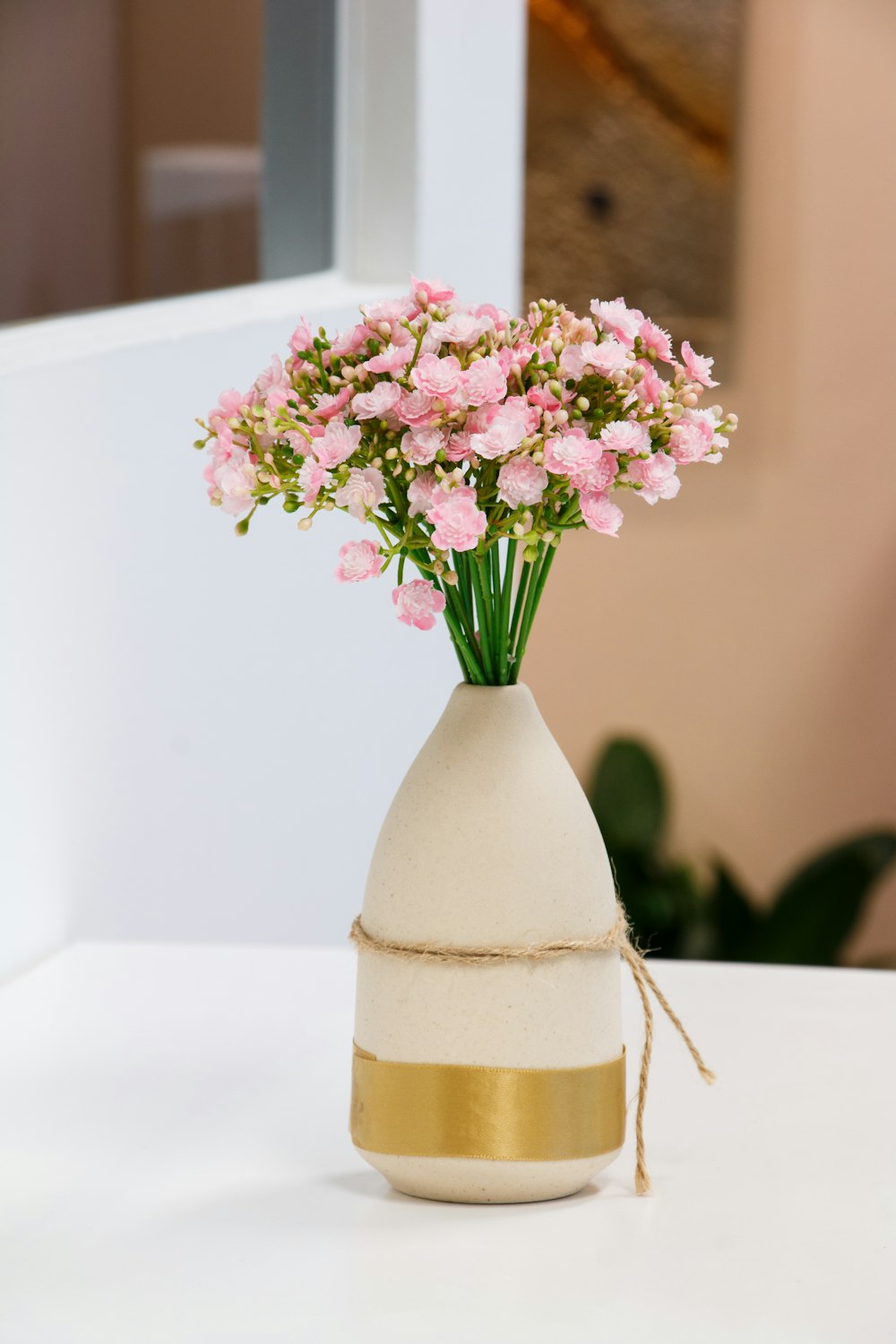 a white vase with pink flowers in it