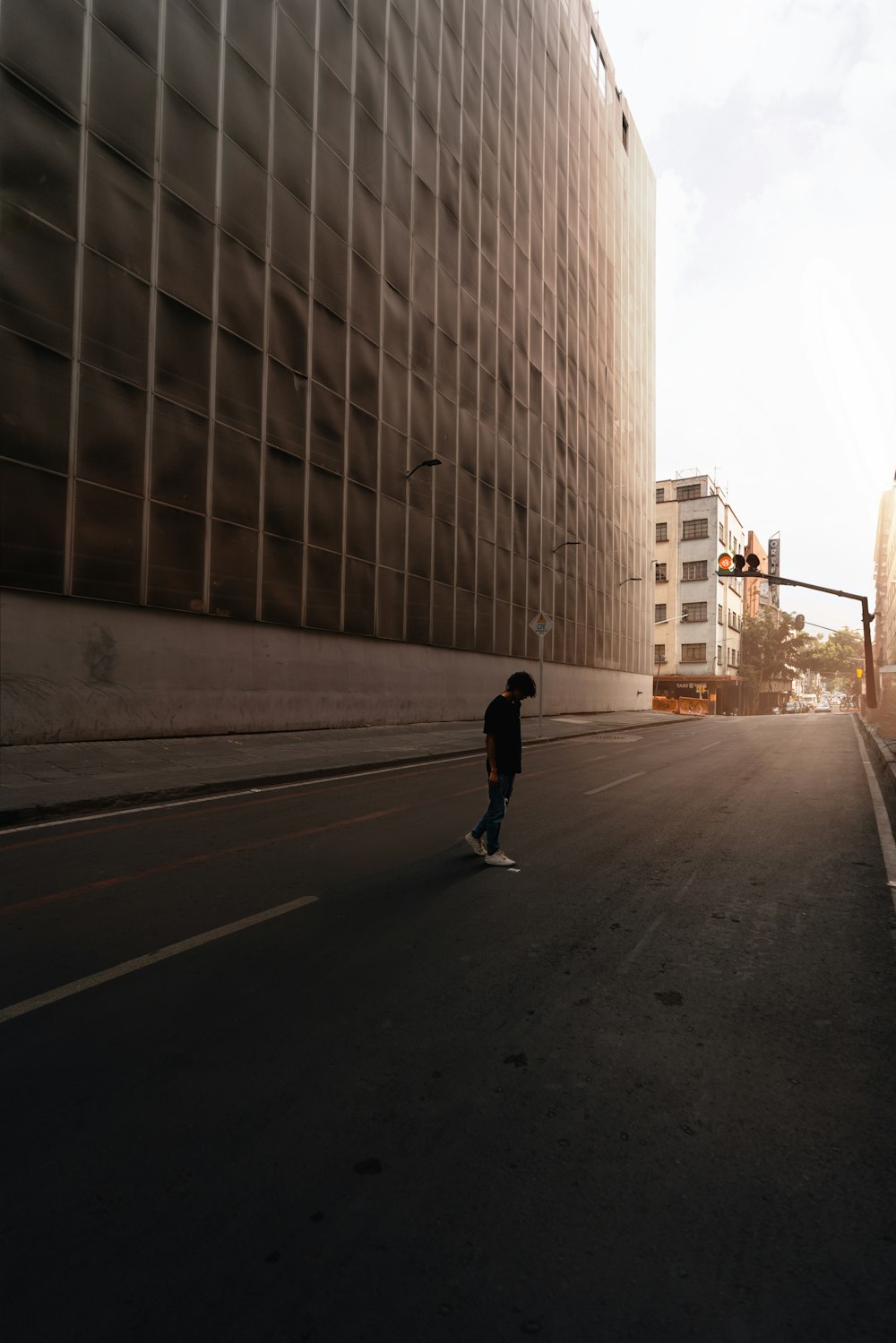 Ein Mann, der auf einem Skateboard eine Straße neben hohen Gebäuden hinunterfährt