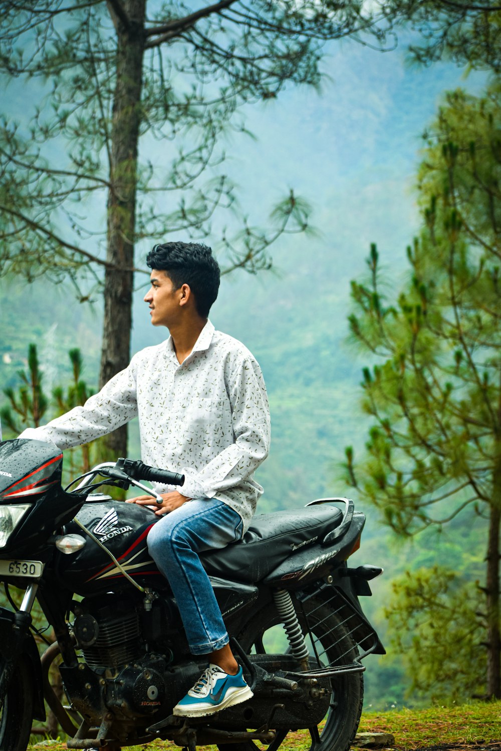 a man sitting on a motorcycle in the woods