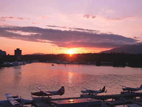 A stunning waterfront view of the sunrise over Vancouver Island's coastline with a peaceful harbor scene.