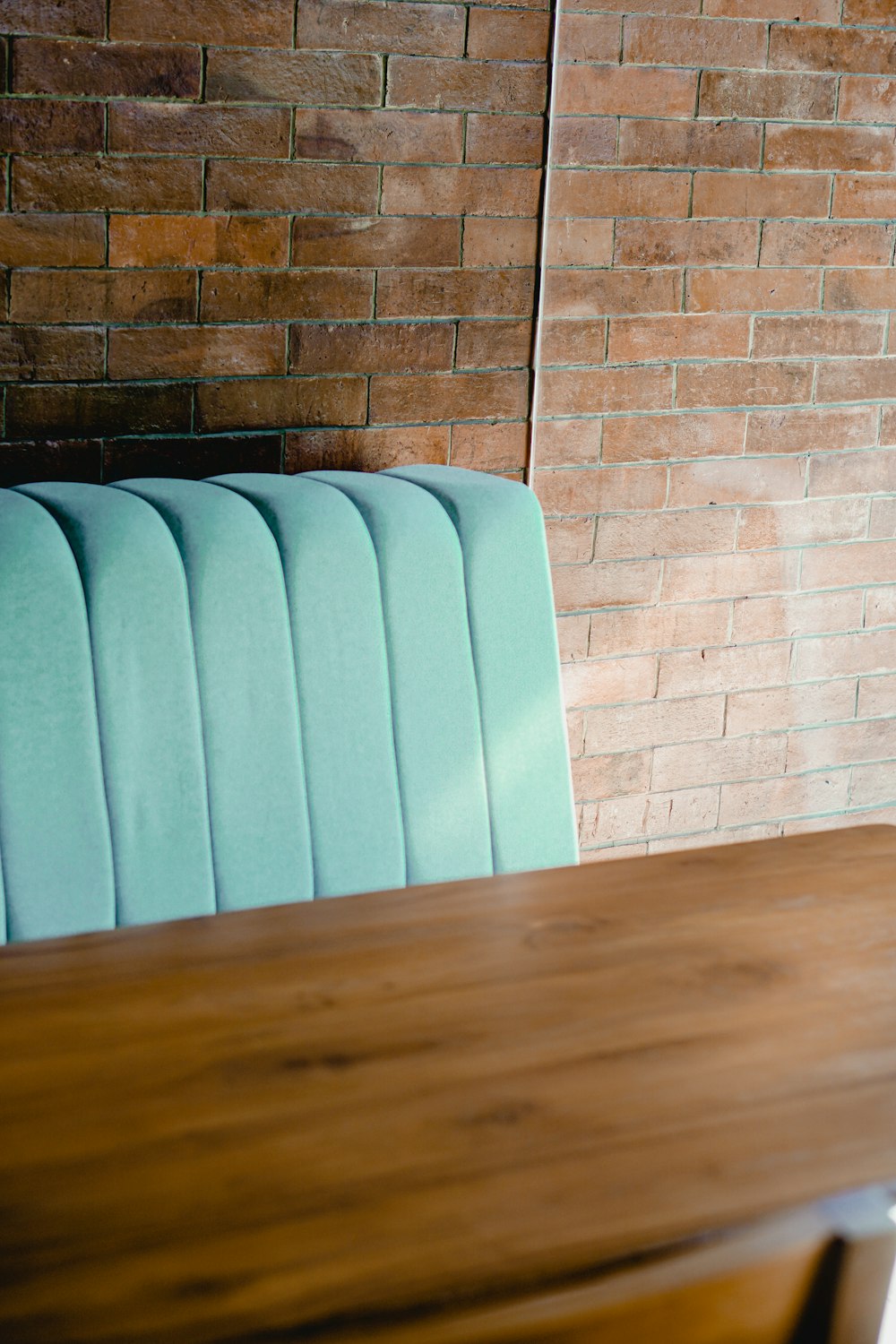 a wooden table with a blue chair next to a brick wall