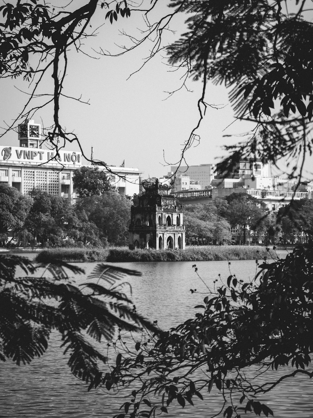 uma foto em preto e branco de um lago com um edifício ao fundo