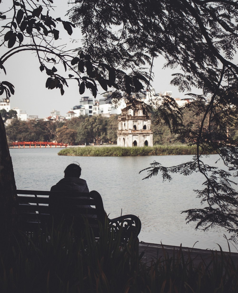 a man sitting on a bench next to a body of water