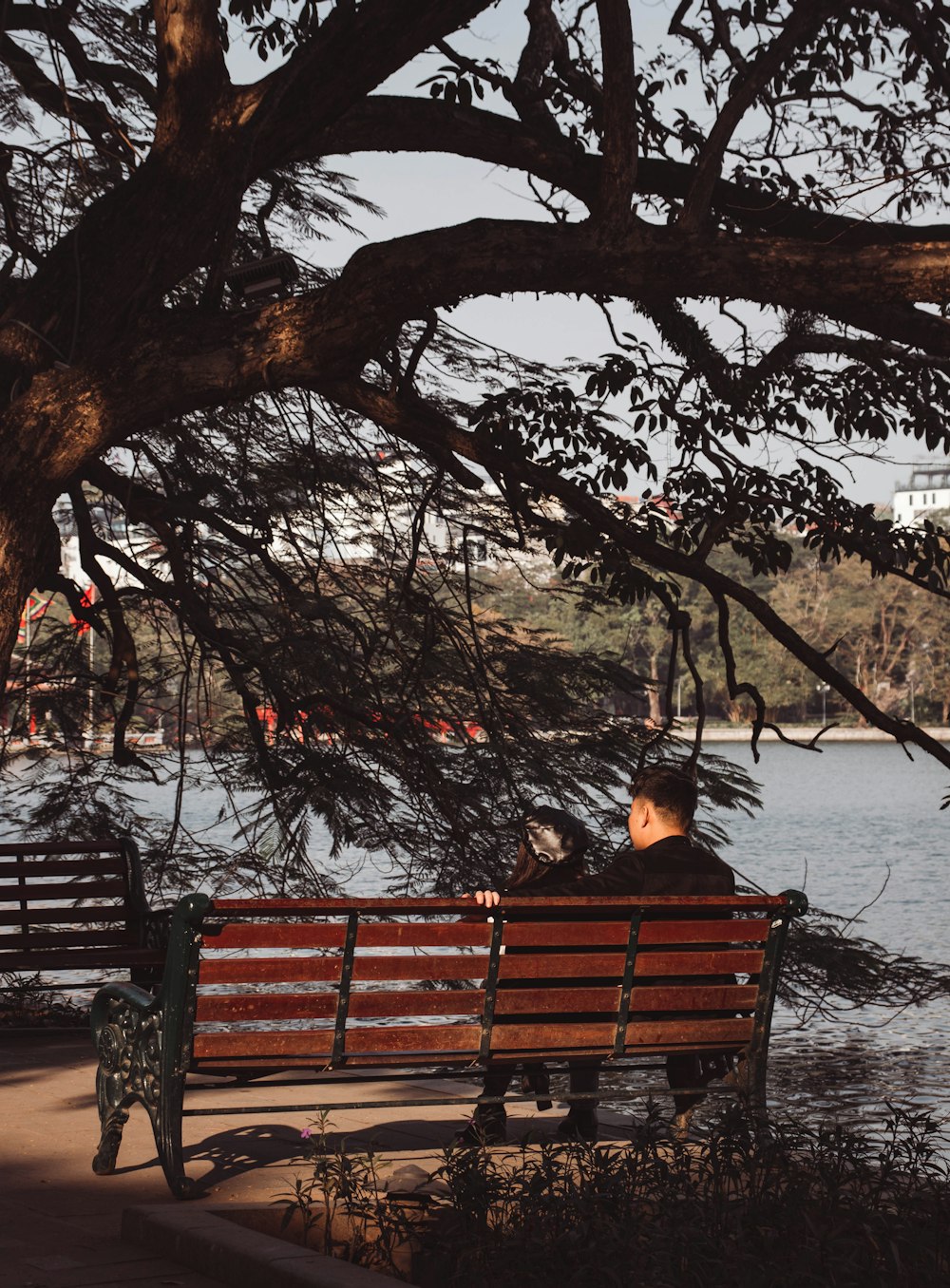 a man sitting on a bench next to a lake