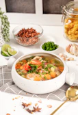 A colorful bowl of homemade soup with herbs on top.