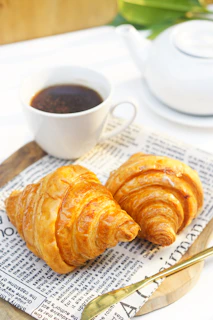 Golden, flaky croissants arranged artfully on a linen cloth with a cup of coffee nearby
